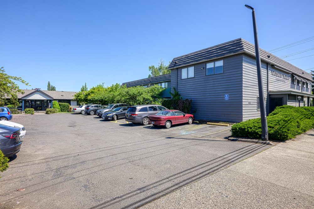 The exterior of a two-story gray building with a sign that reads Waterman House, surrounded by well-manicured hedges